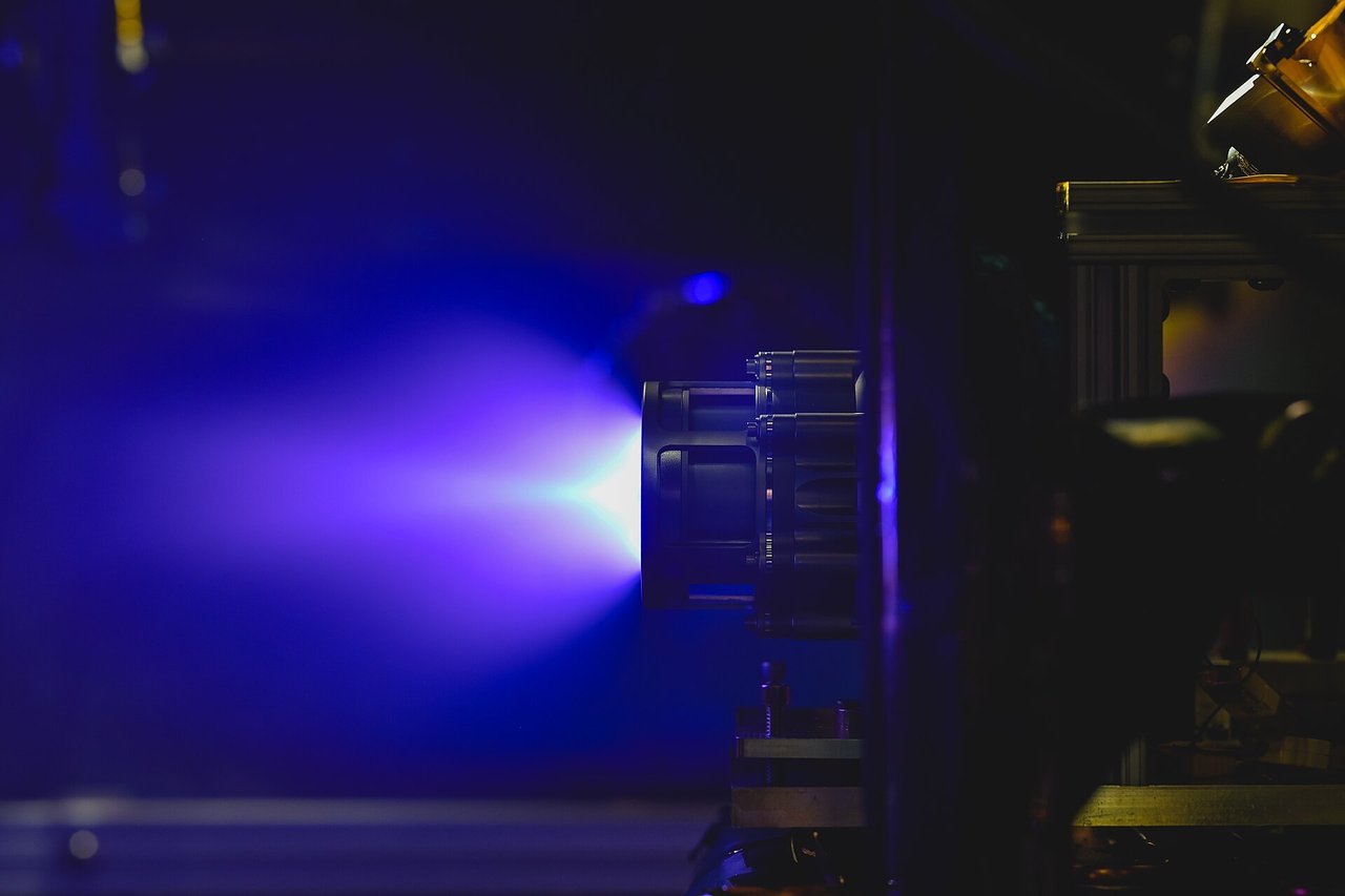 A Hall-effect thruster firing its blue-violet plume in a vacuum chamber