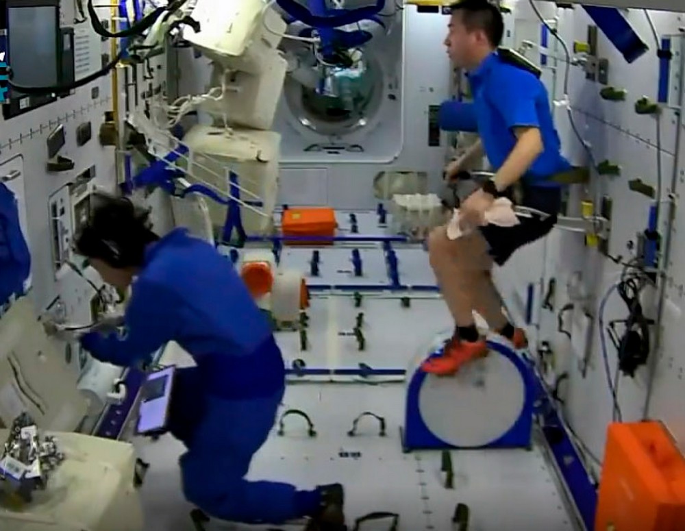 Liu Yang and Cai Xuzhe work among equipment, experiment racks, and restraints in Wentian