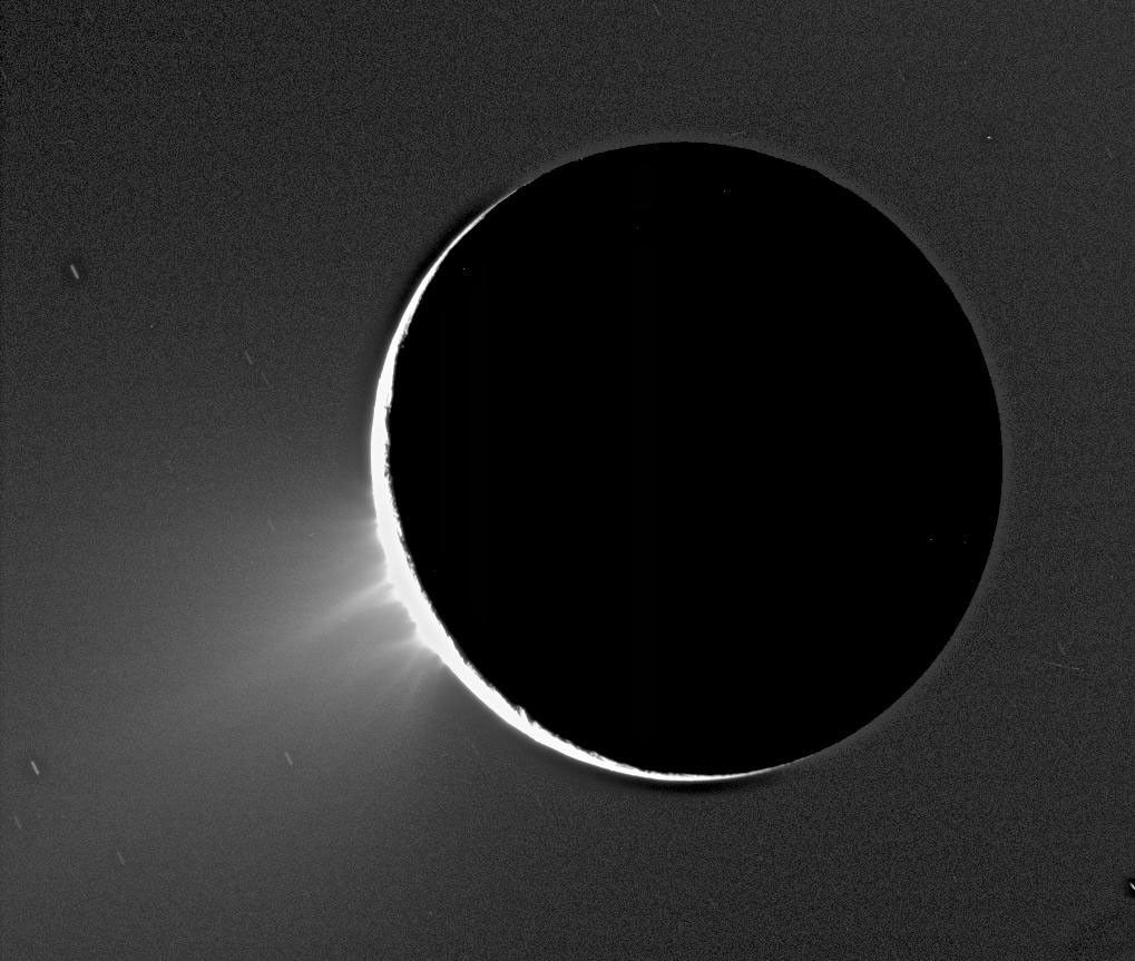 Enceladus im Gegenlicht als Silhouette vor seinen hellen südpolaren Fontänen