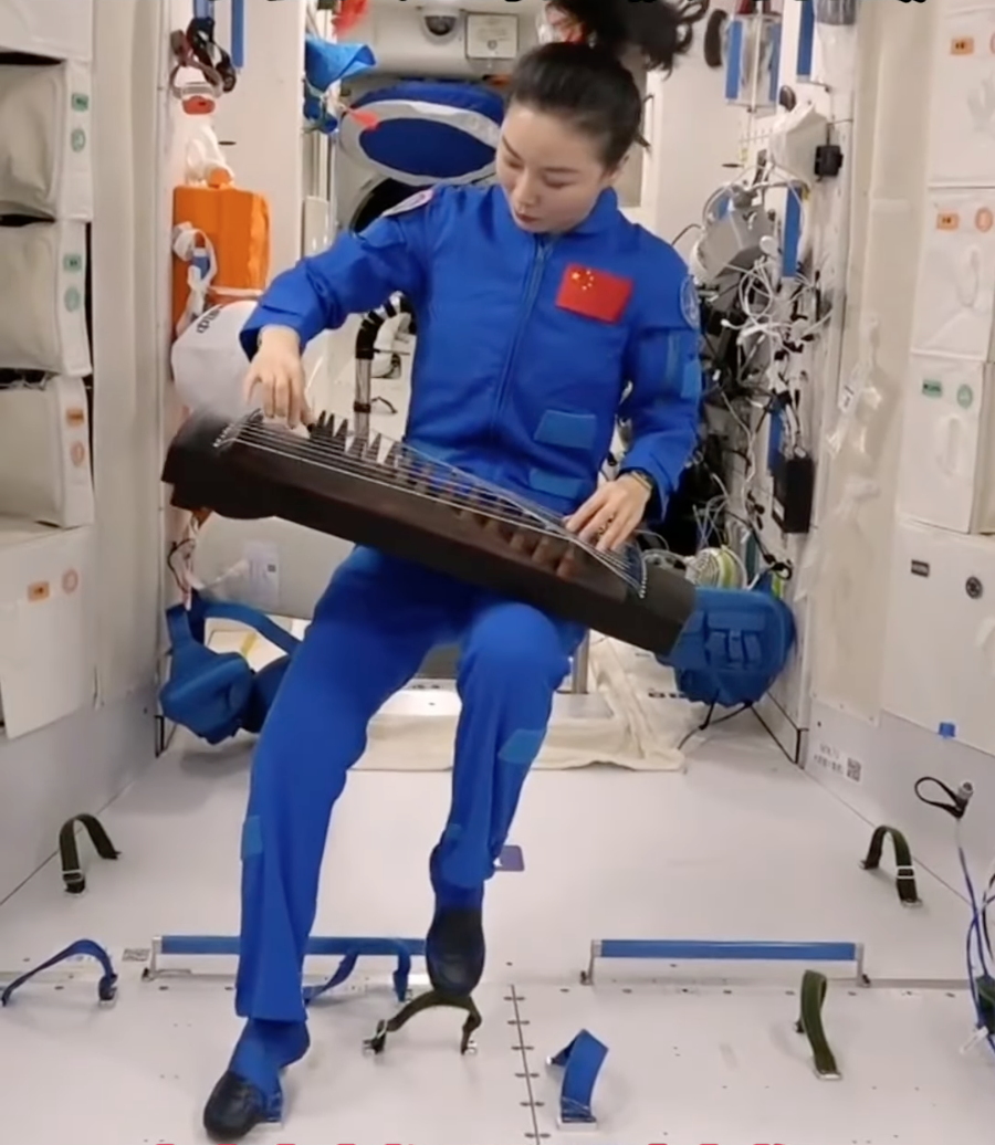 Wang Yaping spielt auf Tiangong Guzheng; in Mikrogravitation müssen sowohl Musikerin als auch Instrument befestigt sein